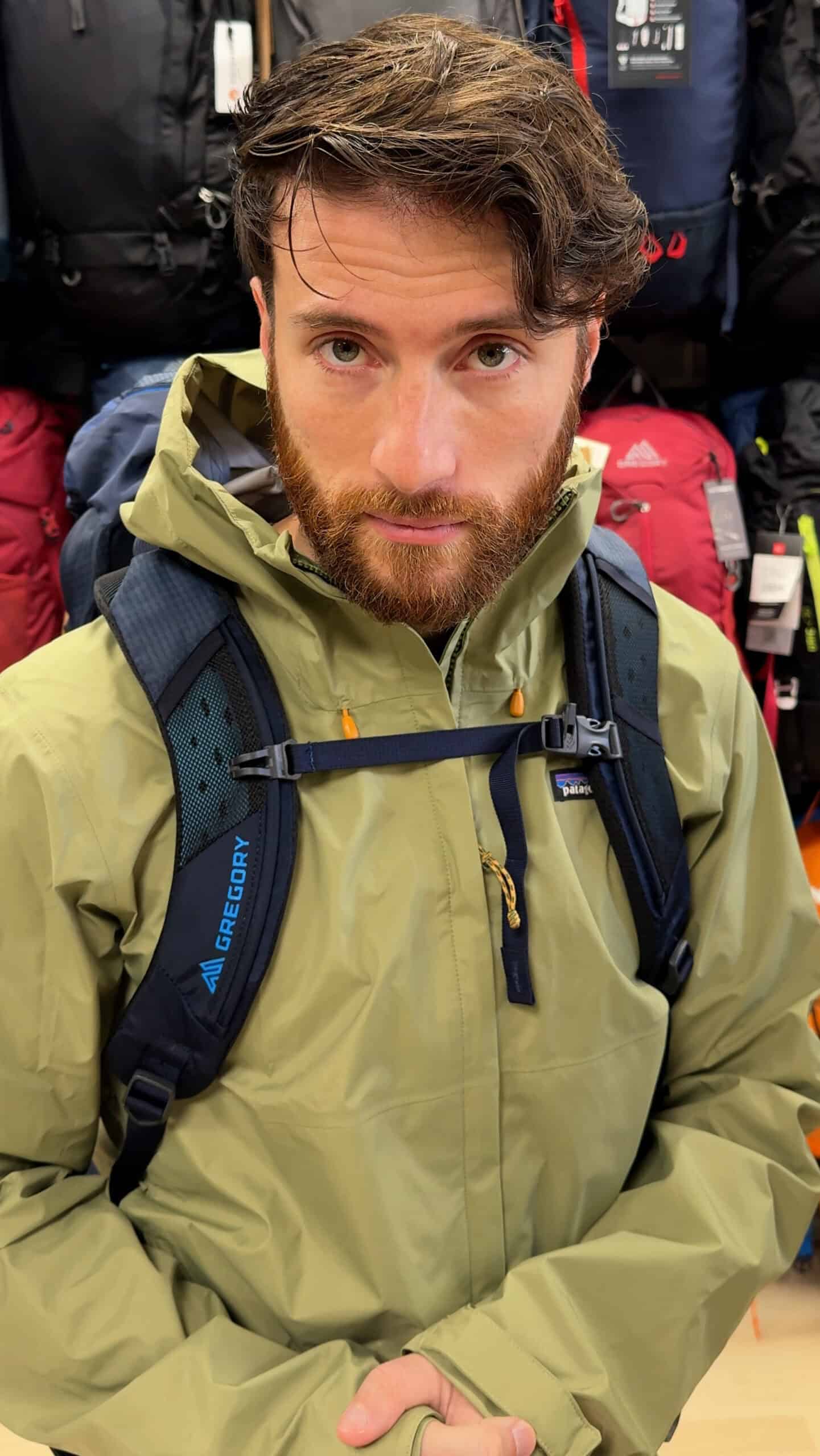 Nico Colucci con impermeabile beige e zaino nero da trekking